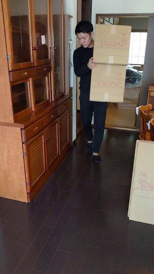 家屋に傷をつけないよう足元に注意してダンボールを搬出するスタッフ