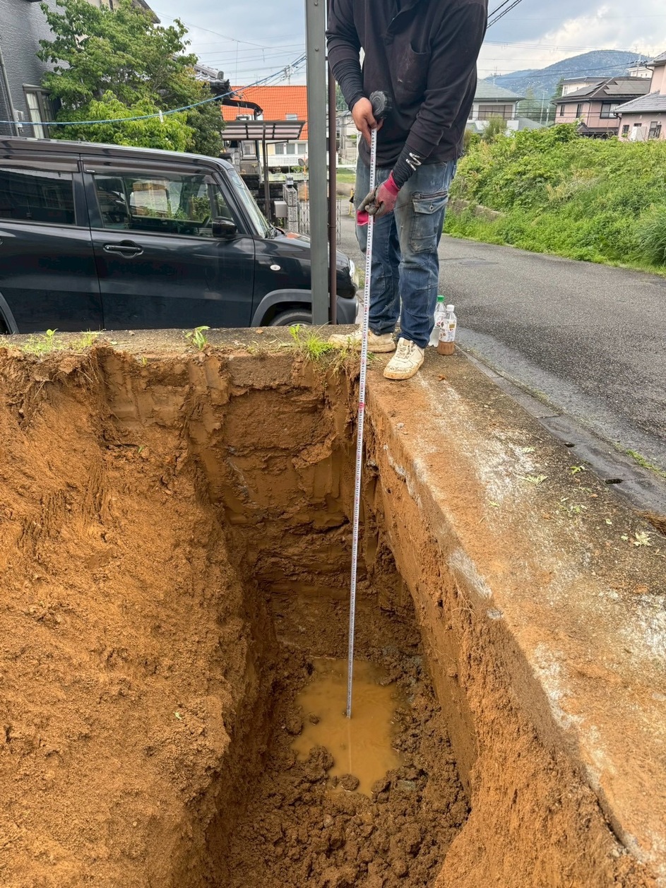 重機で深く掘り進め、作業員がメジャーで深さを測っている衝撃の写真
