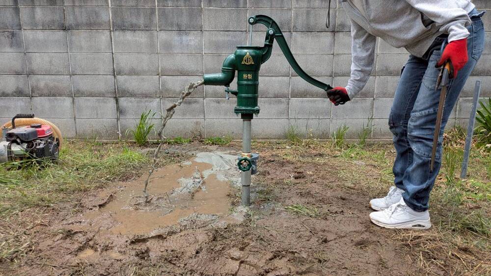 完成した手押しポンプ(ガチャポン)から勢いよく冷たい地下水が出る様子