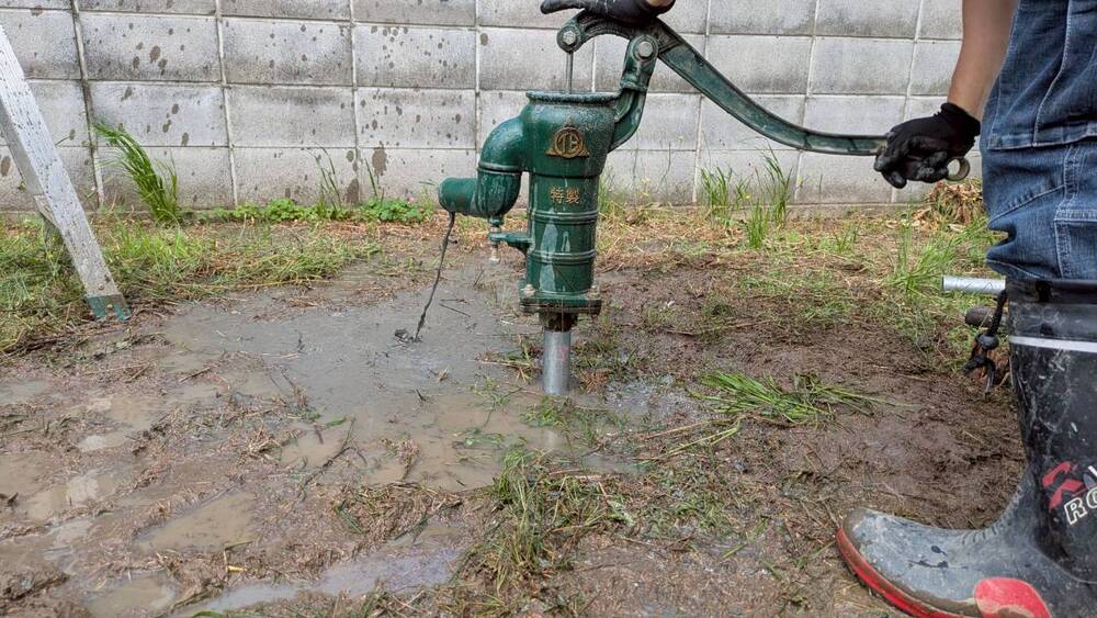 水脈到達後、手押しポンプを取り付けて砂混じりの地下水を汲み上げる様子
